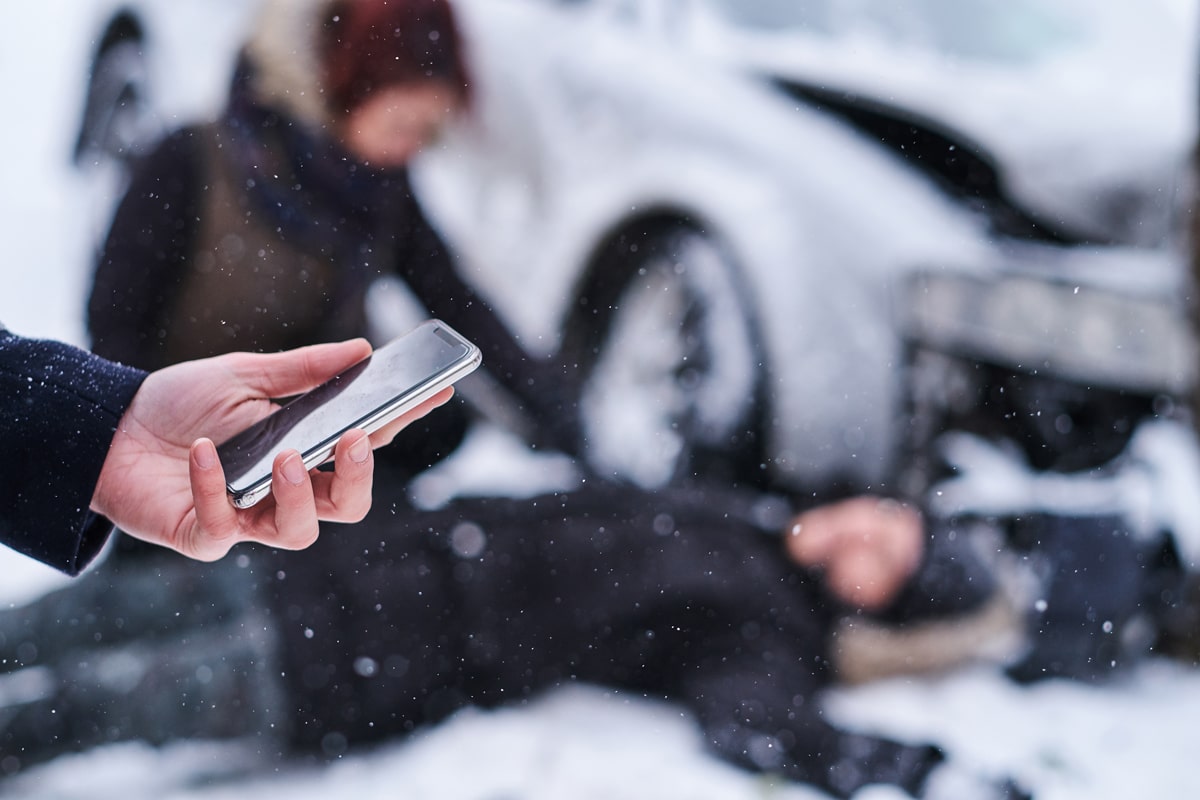 Portland man lying on ground on snow after crash while being attended to by woman as person calls police