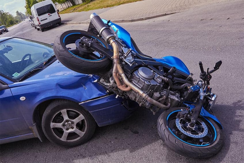 crash aftermath of a blue car and blue motorcycle