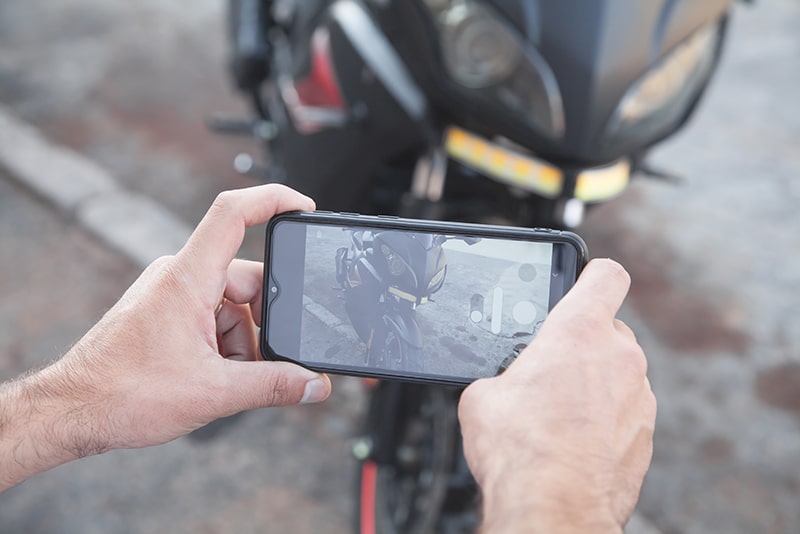 person photographing motorcycle accident damage