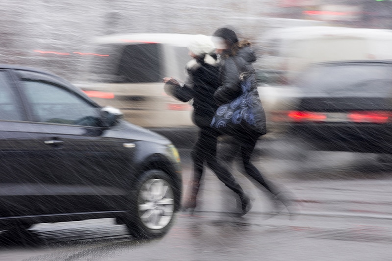 two people crossing in front of car