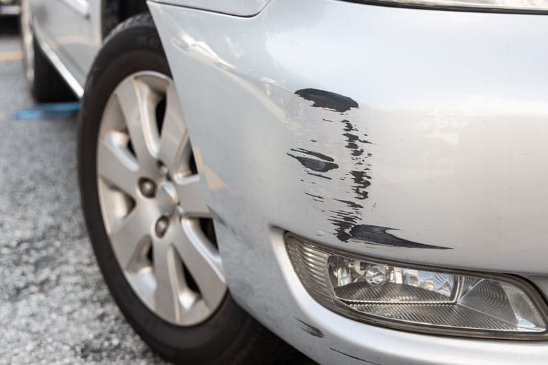 damage on front bumper of white car