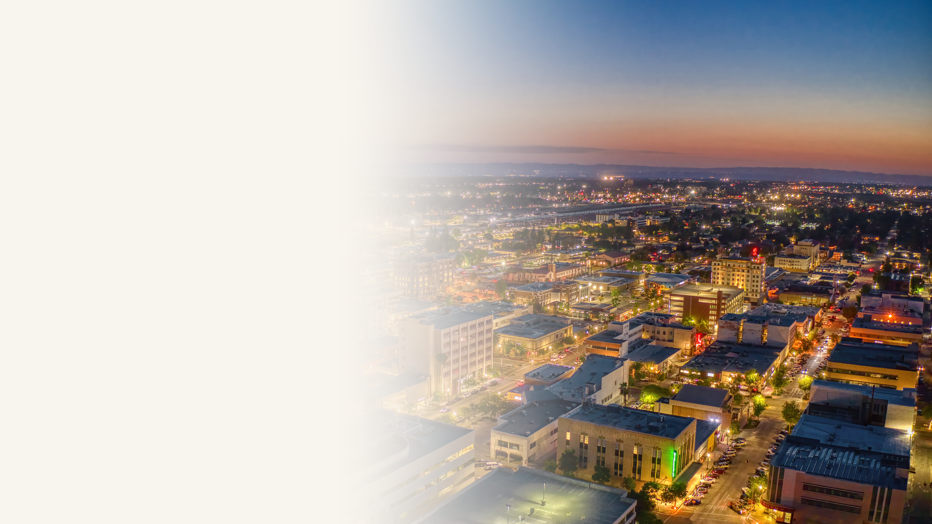 Aerial view of downtown Bakersfield, California at dusk with city lights and the Central Valley horizon