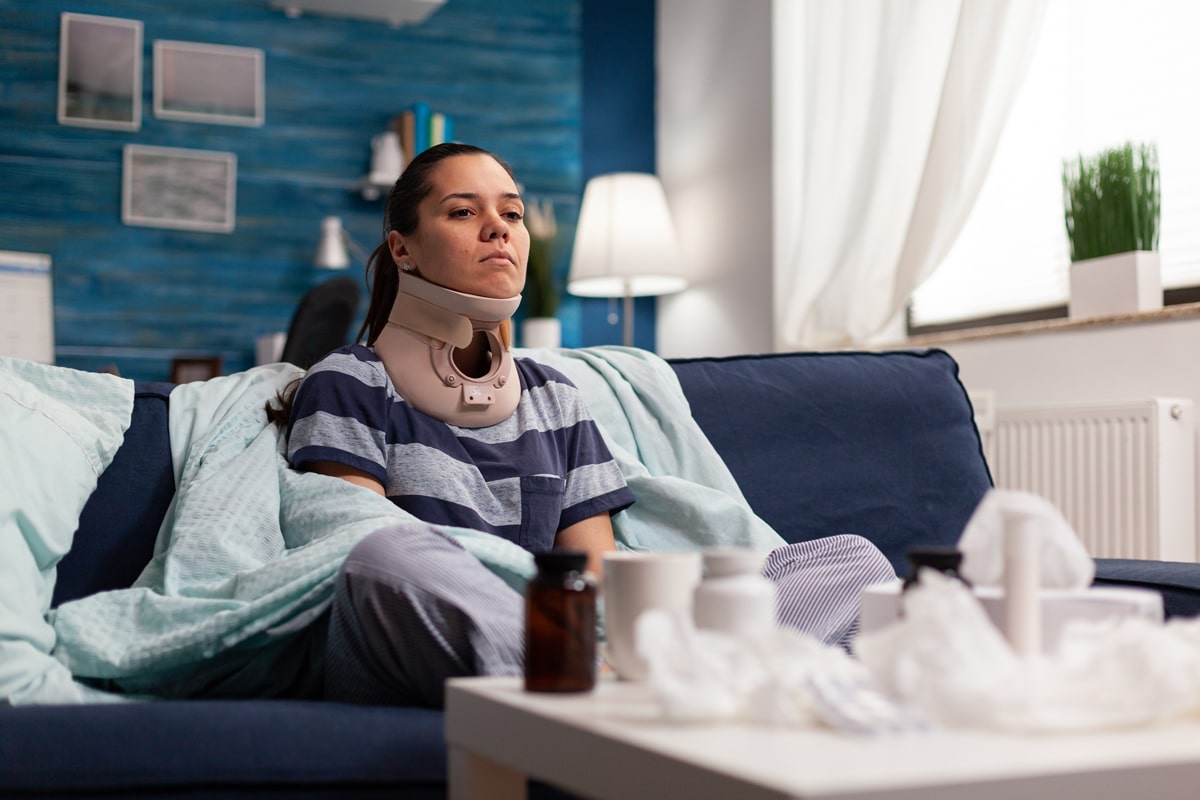 Woman sitting on couch with neck brace on.