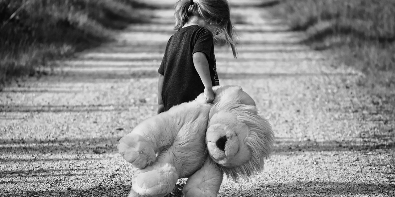 Child, lonely, walking down road with stuffed animal in tow.