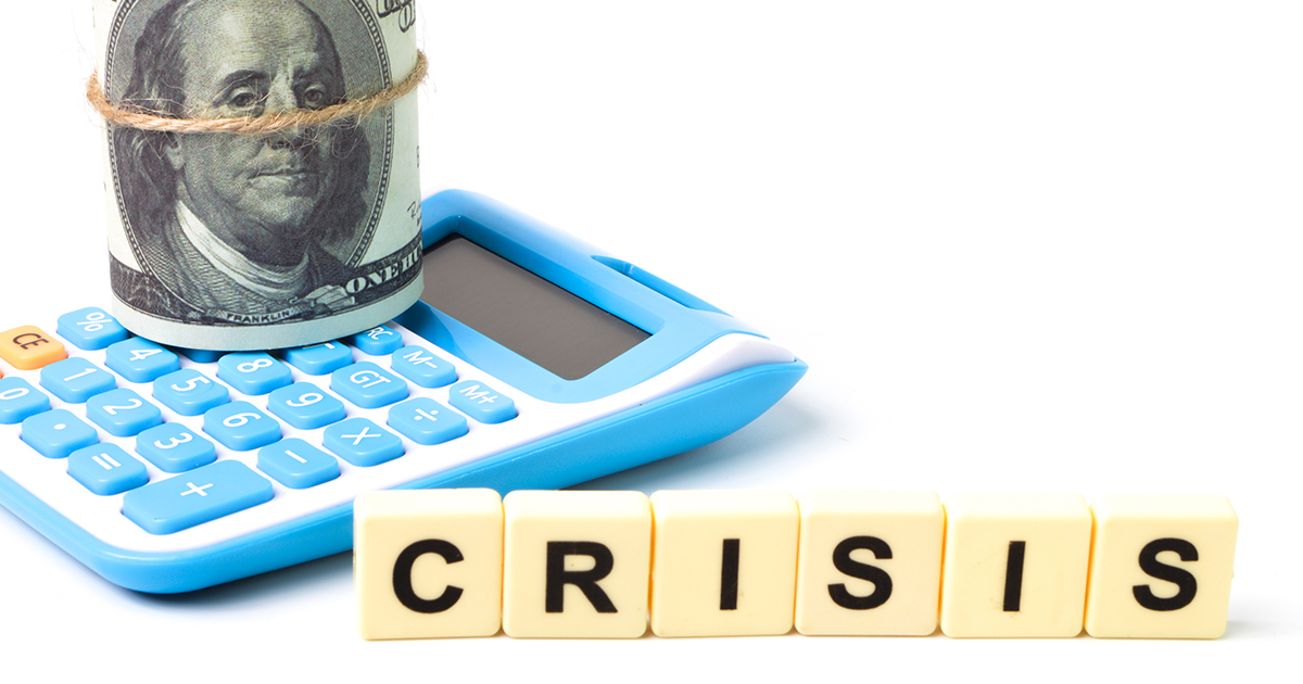 Calculator next to money with the word tiles of crisis.