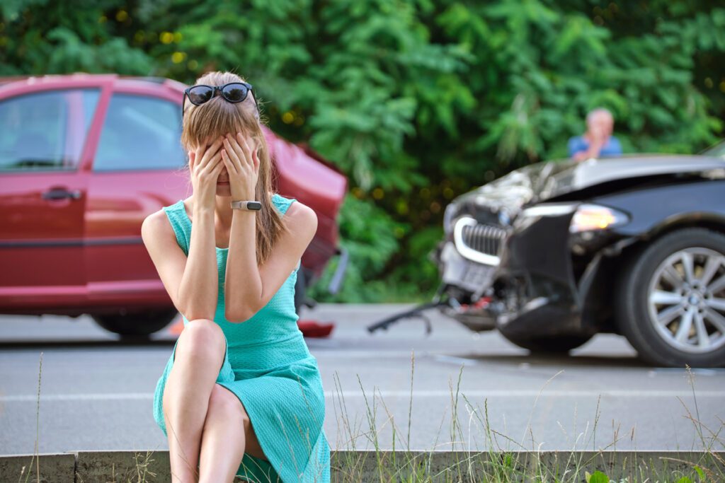 woman holding her head in hands after car accidnet