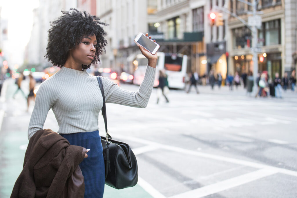 woman signaling with her phone that she is waiting for a rideshare service