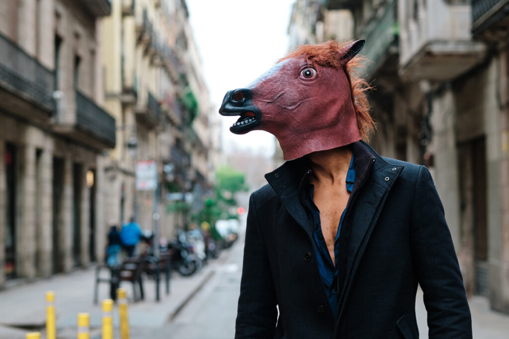 well dressed man in street with horse mask on
