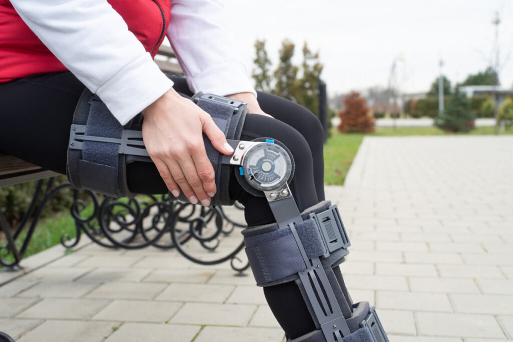 woman adjusting knee brace on park bench
