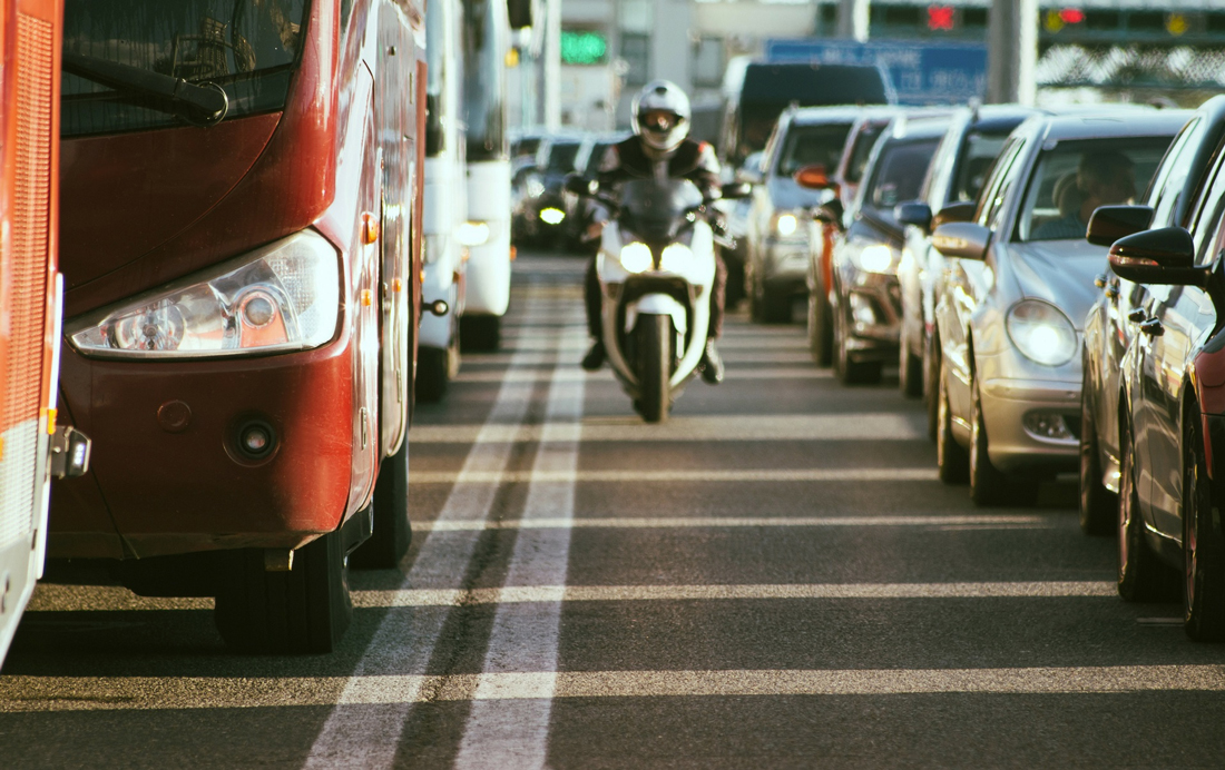 motorcyclist riding in middle lane between vehichiles