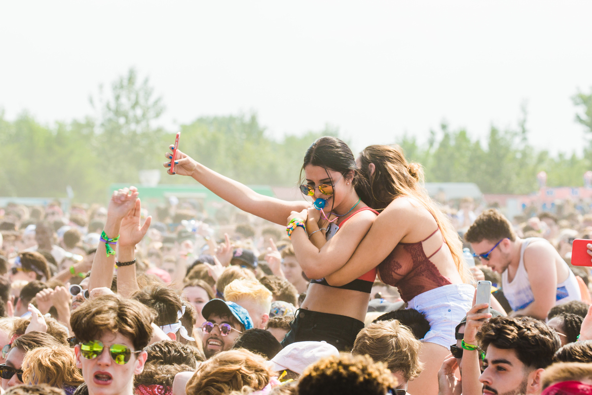 two girls on the shoulders of their friends at concert