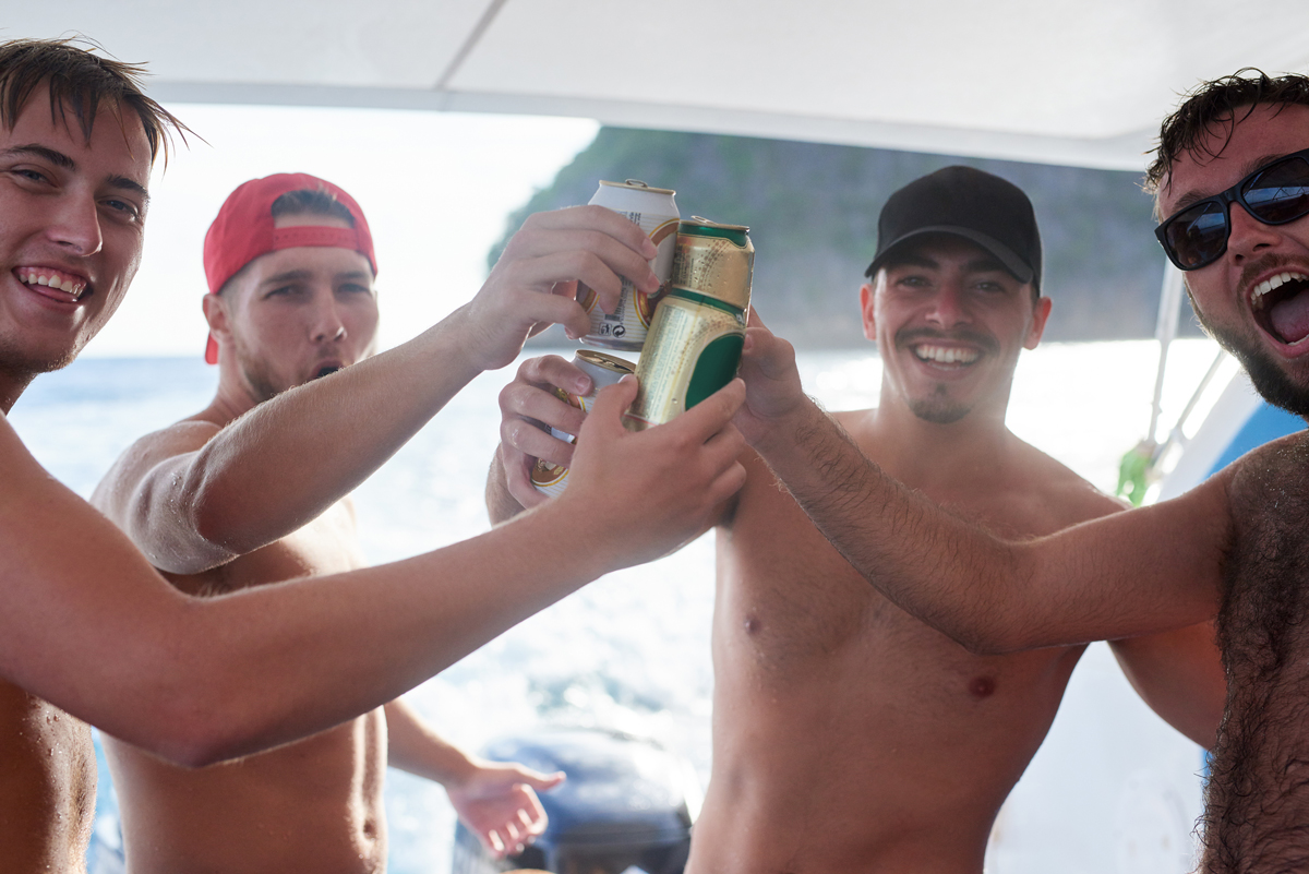 four young men drinking beer on a boat