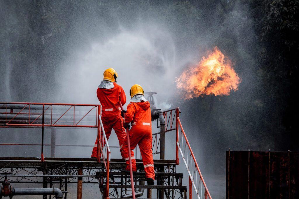 two firemen extinguishing flames in a plant fire