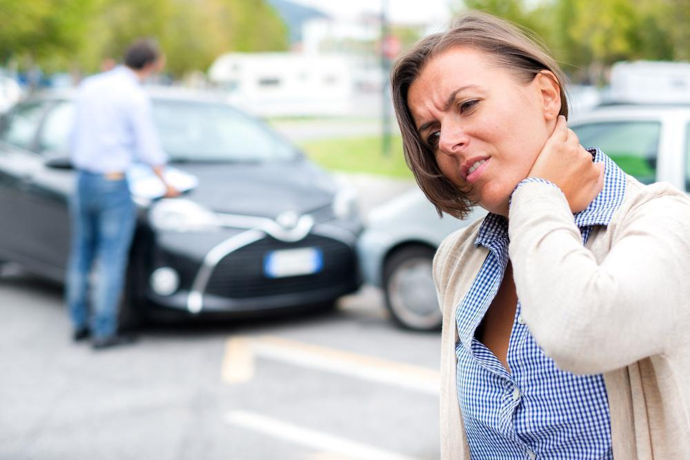 Woman wincing in pain from neck after a car accident