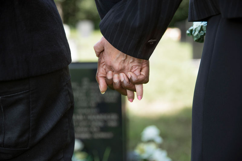 Hombre y mujer cogidos de la mano en un funeral