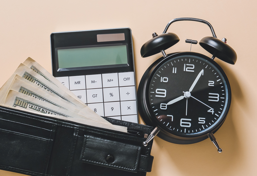 Image of a wallet with 100-dollar bills, a calculator, and a clock.