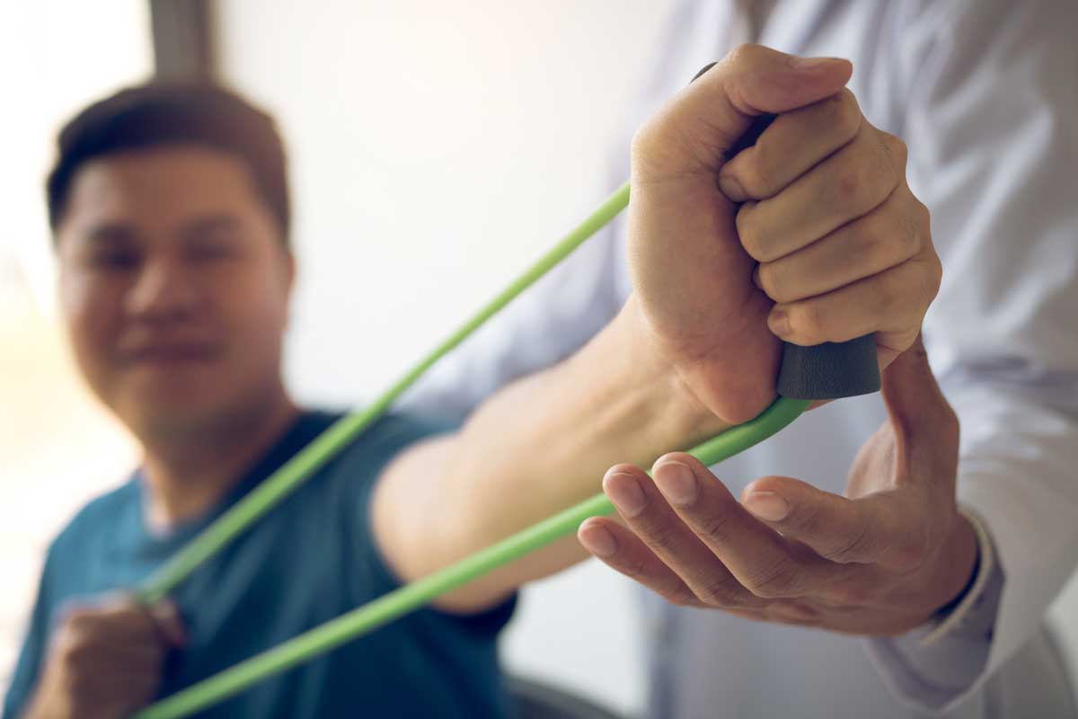 image of a man using elastic band to test strength while a physician observes